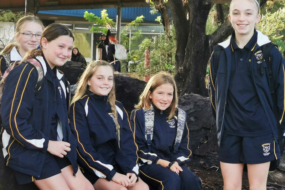 Students in school uniform sitting on rocks in front of the school