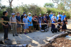 Group of people on a path in beautiful bush setting watching the cutting of a yellow ribbon