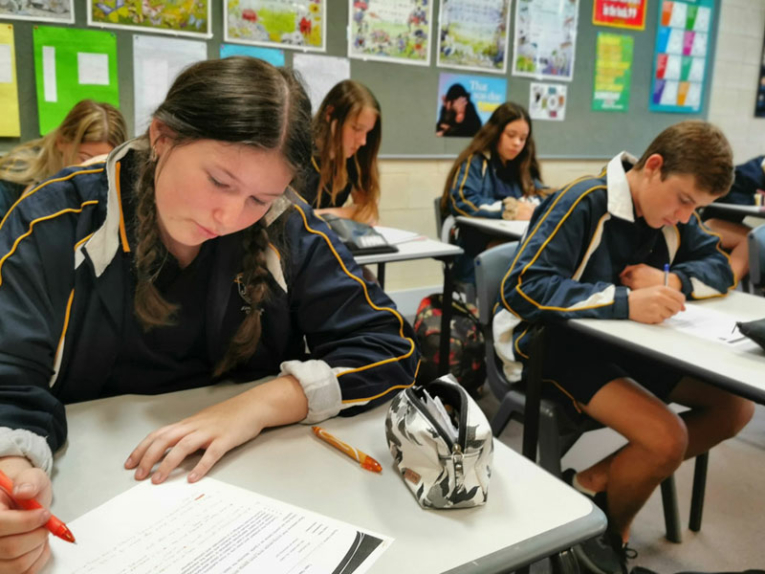 Students sitting at tables in a classroom doing schoolwork